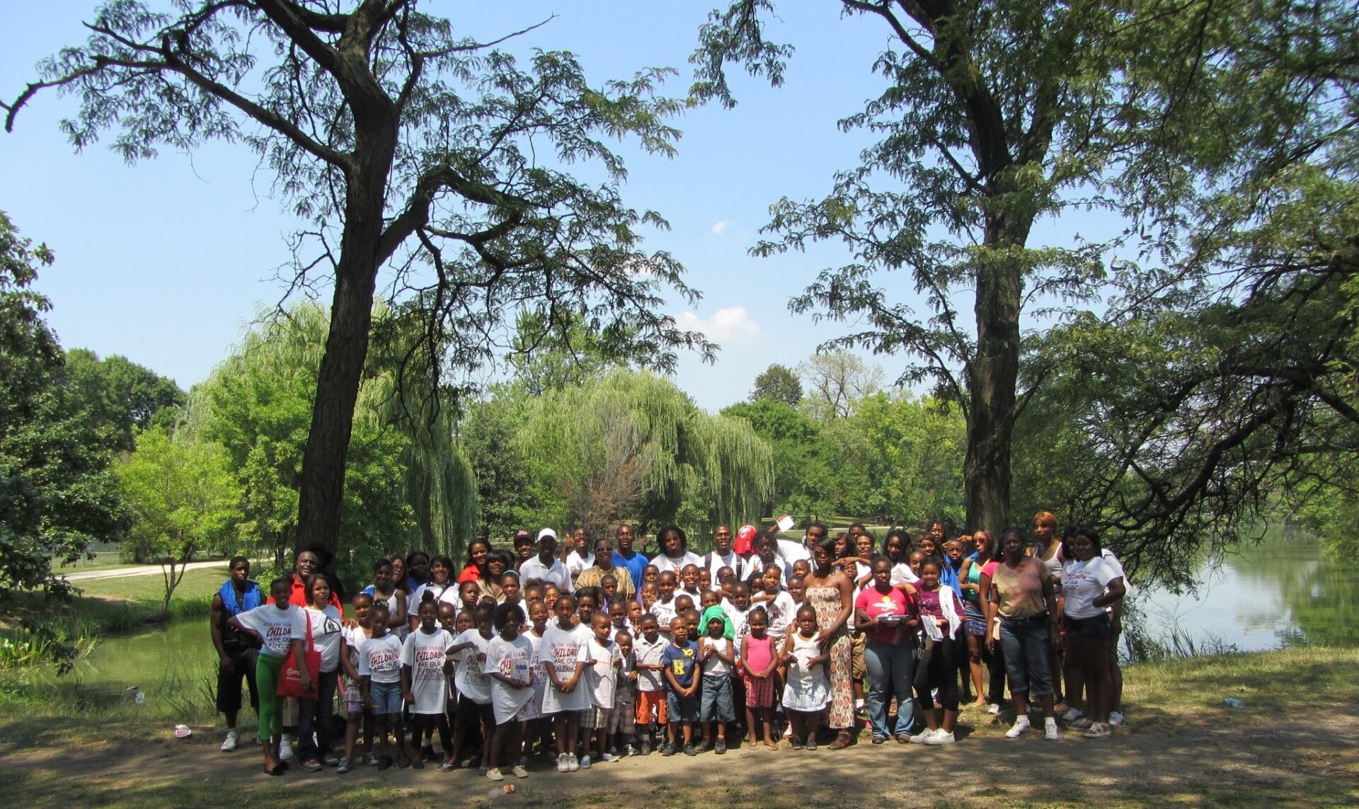 A group of women and children posing for a picture near a lake